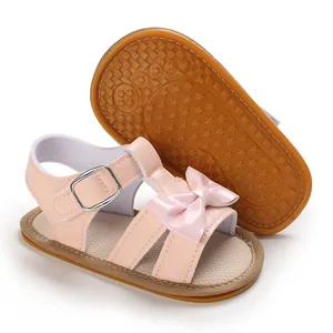 Detail view of pink baby girl sandals with non-slip star pattern rubber sole and bow.