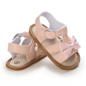 Detail view of pink baby sandals with shiny bow decoration and non-slip rubber sole