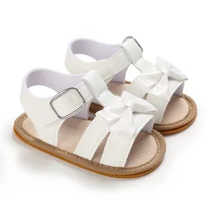 Detailed close-up of white baby girl sandals with bow tie and anti-slip rubber sole