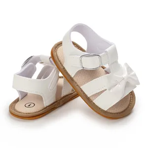 Detailed view of white baby girl sandals featuring a large bow and non-slip rubber sole