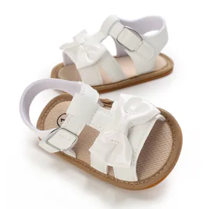 Detailed macro view of white baby girl sandals with decorative bow and anti-slip rubber sole