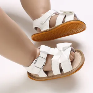 Detailed view of white baby girl sandals with bow accent and anti-slip rubber sole.