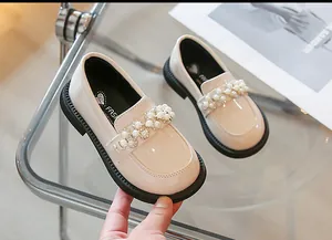 Close-up view of beige children's patent leather loafers with elegant pearl and rhinestone details