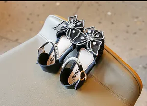Détail de chaussures de princesse noires pour filles avec nœuds en strass et perles