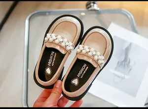 Close-up detail of girls' beige princess loafer shoes with pearls and crocodile texture