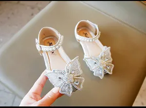Gros plan de chaussures de princesse pour filles avec papillon en strass et perles.