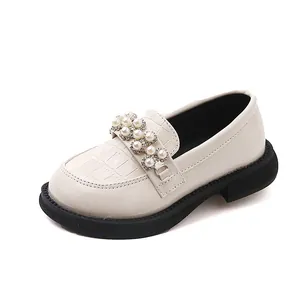 Detail view of cream children's loafer with pearl embellishments and crocodile texture upper