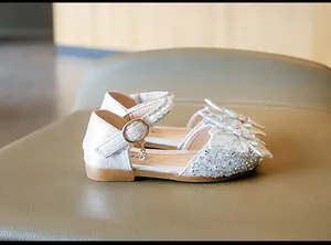 Détail de chaussures argentées scintillantes pour fille avec perles et nœud papillon décoratif