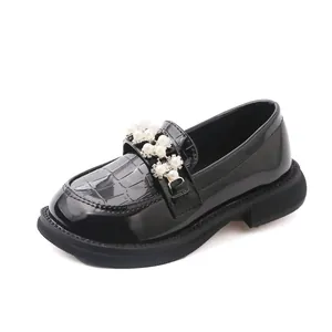 Detailed view of girls' black patent leather loafers with pearl and rhinestone decor