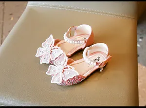 Détail de chaussures de fille pailletées roses avec grand nœud papillon en perles.