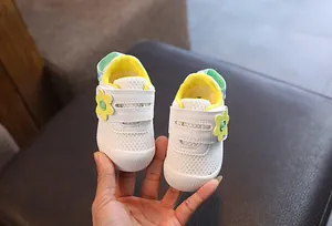 Detalle de los zapatos de malla blanca transpirable para bebé niña con flor amarilla