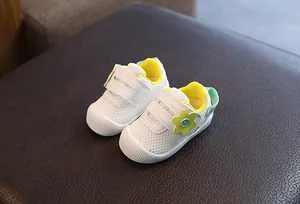 Vista detallada de zapatos de malla blanca para bebés con una bonita flor amarilla