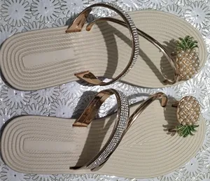 Dettaglio di sandali piatti da donna con cinturini in strass e ciondolo a forma di ananas