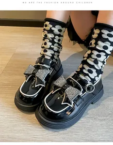 Detalle de zapatos de charol negro para niña con un lazo de diamantes de imitación