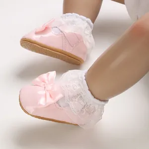 Detail view of pink baby princess shoes featuring white lace and satin bow for newborns