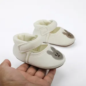 Detailed view of off-white baby shoes with a cute bunny patch and Velcro strap.