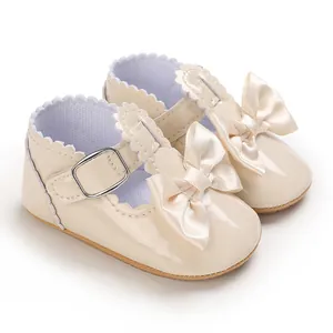 Close-up of beige baby girl princess shoes with satin bow and elegant wavy trim