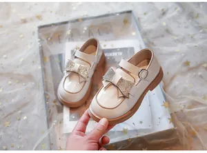 Detalle de los zapatos de charol para niña con un lazo brillante de diamantes.