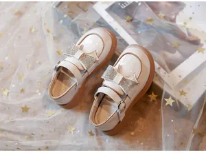 Primer plano de zapatos de charol beige para niña con lazos de pedrería