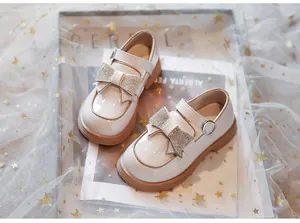 Primer plano de zapatos de cuero para niña estilo británico con lazo de cristal
