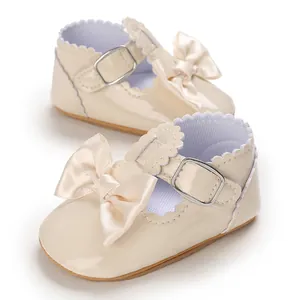 Close-up of cream patent leather baby princess shoes with a soft satin bow detail.