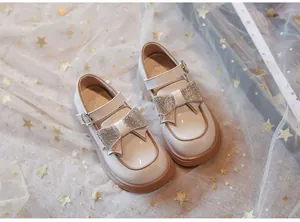 Detalle de zapatos Mary Jane de cuero crema para niña con gran lazo de pedrería