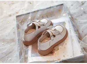 Detalle de zapatos Mary Jane para niña con lazo de pedrería brillante y suela plataforma.