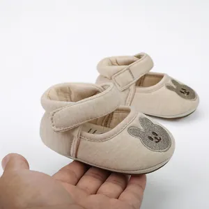 Close-up of beige baby walking shoes with cute bunny embroidery and velcro strap.