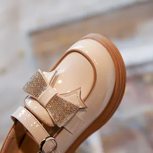 Elegantes zapatos de charol beige para niña con detalle de lazo de strass brillante