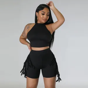 Front view of black sleeveless halter crop top and fringed shorts set on female model