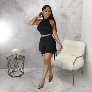 Black sleeveless halter neck top and fringe shorts set shown in a stylish marble room