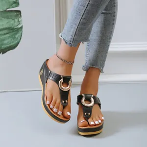 Détail de tongs à talons compensés noires avec motif ajouré et boucle métallique