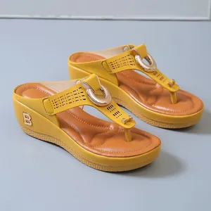 Detail showing the yellow wedge flip-flops with hollow-out straps and metallic B logo.