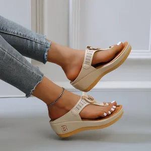 Vue latérale de tongs compensées bises avec design ajouré et logo B doré chic.