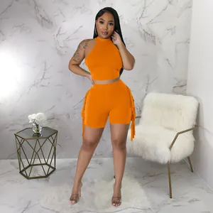 Detailed view of orange two-piece set featuring fringe shorts and high-neck top