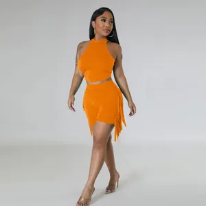 Full body view of a model in a bright orange sleeveless set with trendy side tassel fringe