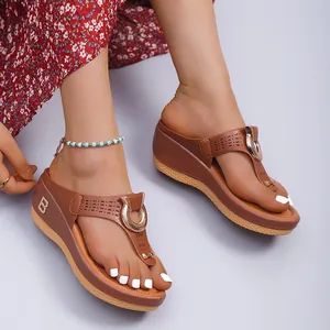 Détail de sandales compensées marron avec motif ajouré et décoration en anneau