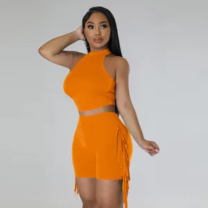 Chic two-piece orange sleeveless set featuring a halter crop top and tasseled shorts