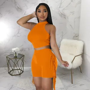 Detail view of a vibrant orange two-piece set with a halter top and fringe shorts.
