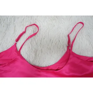 Detailed view of adjustable thin spaghetti straps and U-neckline on vibrant magenta satin dress