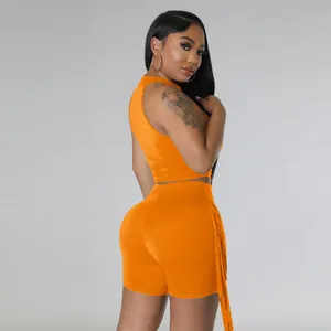 Detailed rear view showing the orange sleeveless crop top and fringe detail on shorts