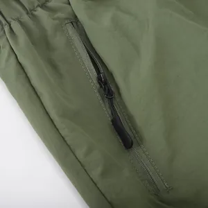 Macro detail showing the durable black zipper pocket on olive green men's cargo shorts.