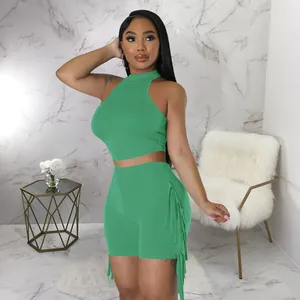 Fashionable green two-piece outfit featuring a halter sleeveless crop top and fringe shorts