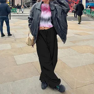 Fashionable woman wearing black loose-fit drawstring cargo pants in an outdoor city setting