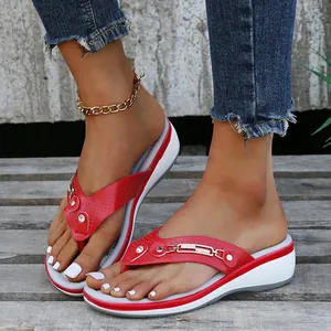 Tongs compensées rouges élégantes avec strass présentées sur un vieux pont en bois.