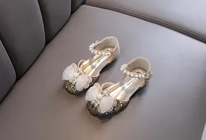 Hochwertige Nahaufnahme goldener Prinzessinnenschuhe für Mädchen mit Perlen und Schleifen
