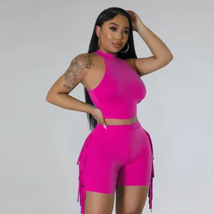 Detailed view of women's two-piece pink set featuring sleeveless crop top and tassel shorts