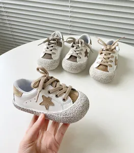 Nahaufnahme eines weißen Baby-Lauflernschuhs mit braunem Stern und strukturierter Gummikappe.