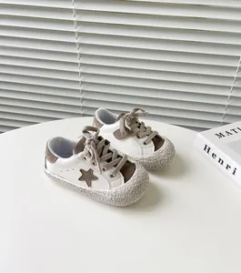 Nahaufnahme von weißen und braunen Lauflernschuhen für Kleinkinder mit Sternenmuster
