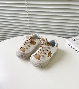 Nahaufnahme von weißen Kleinkinderschuhen mit braunem Sternen-Patch und Gummisohle.